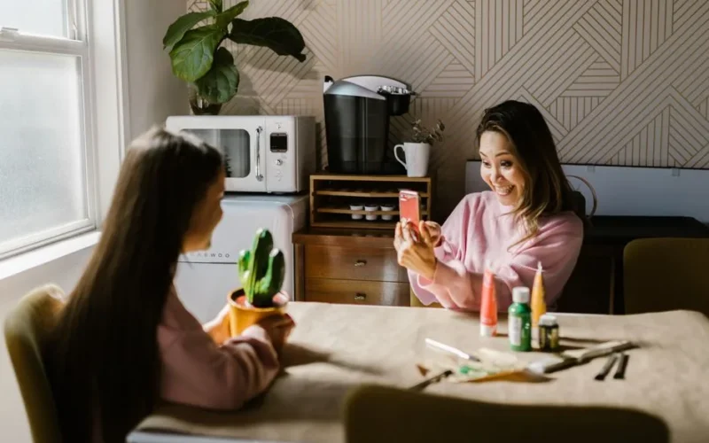 A mother and daughter enjoy a crafting session at their kitchen table, capturing a joyful moment.