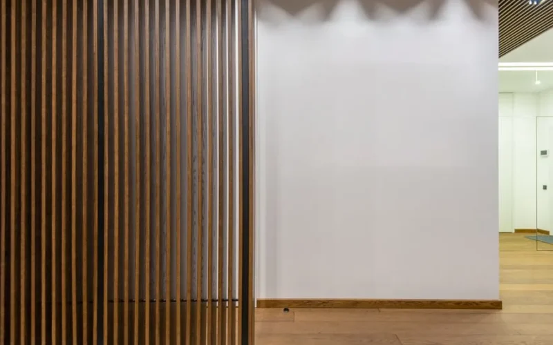 Creative decorative thin wooden partitions placed in spacious corridor of stylish modern apartment with white wall and parquet at home