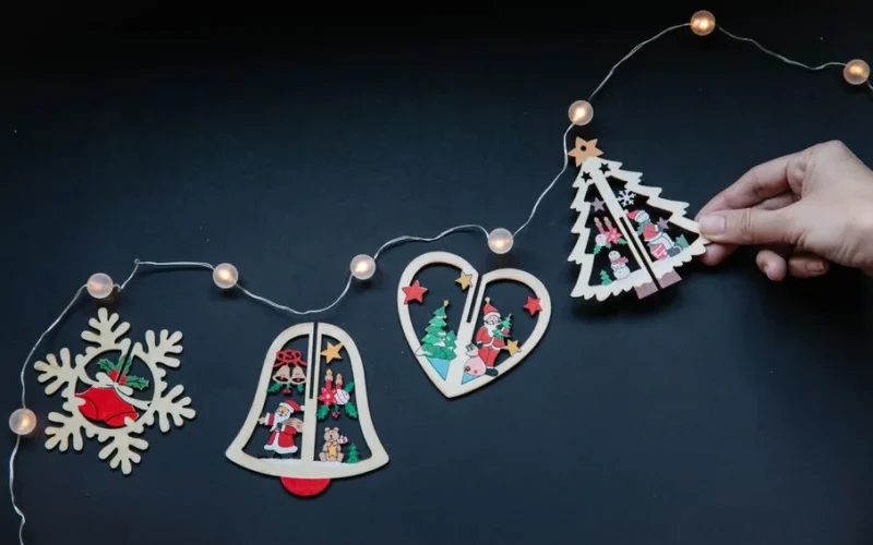 From above unrecognizable woman making line of pieces for handmade garland for Christmas party decorations