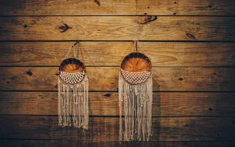 Handmade macrame and wicker baskets on warm wooden wall, perfect for rustic decor.