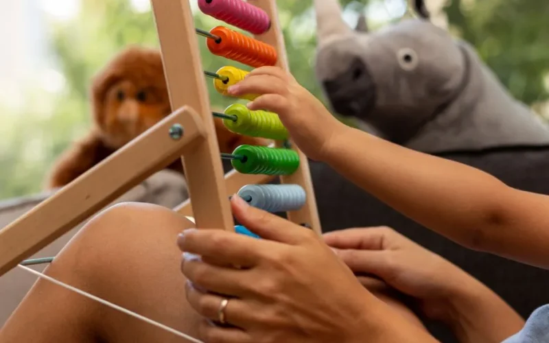 Child's hand playing with a colorful wooden abacus, enhancing early math skills in a playful home setting.