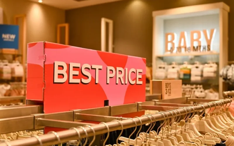Image of a baby clothing store interior with a prominent 'Best Price' sign on display rack.