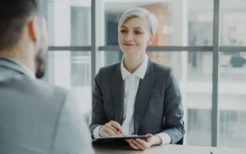 Confident woman interviewing candidate in a modern office. Ideal for business and HR visuals.