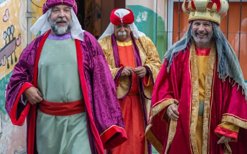Three men dressed as the Magi in a colorful street festival, celebrating tradition and joy.