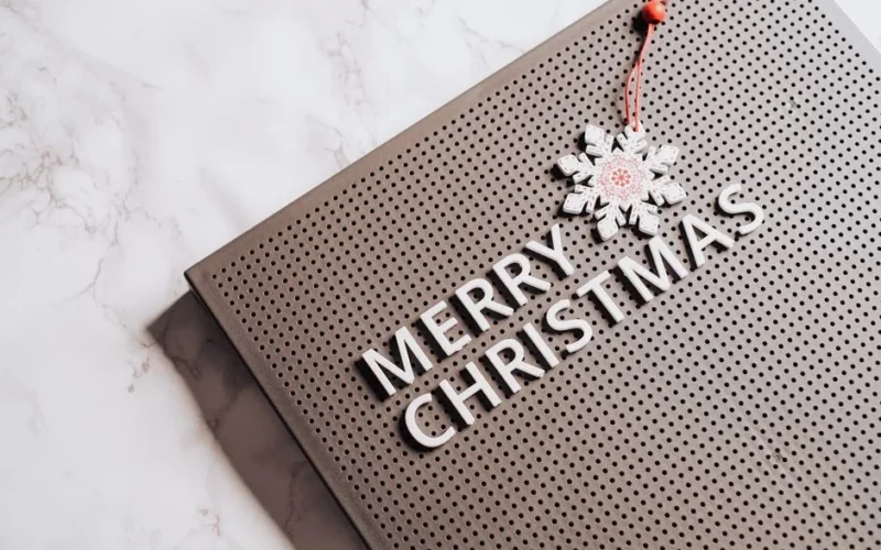 A festive Merry Christmas message displayed on a brown pegboard with snowflake decoration.