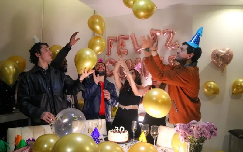 Vibrant birthday party with friends celebrating amidst balloons and festive decorations.