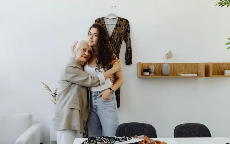 A grandmother and granddaughter share a tender hug in a cozy indoor setting, emphasizing family bonds.
