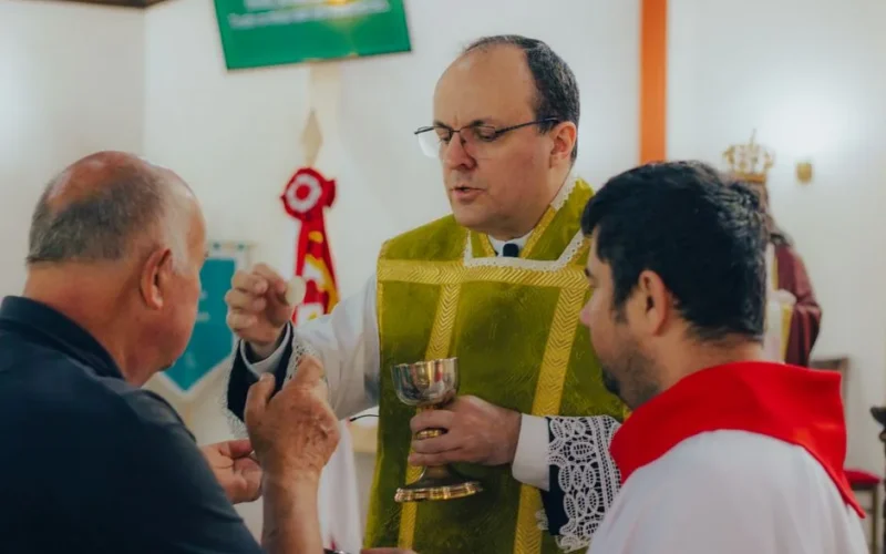 A priest administering Holy Communion to men during a religious service inside a church.