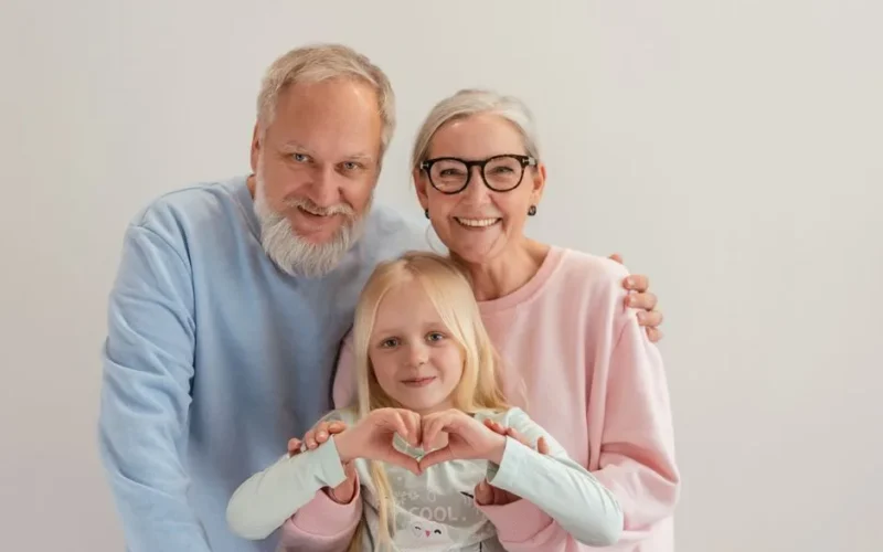Grandparents and granddaughter share a joyful moment, symbolizing love and family unity indoors.