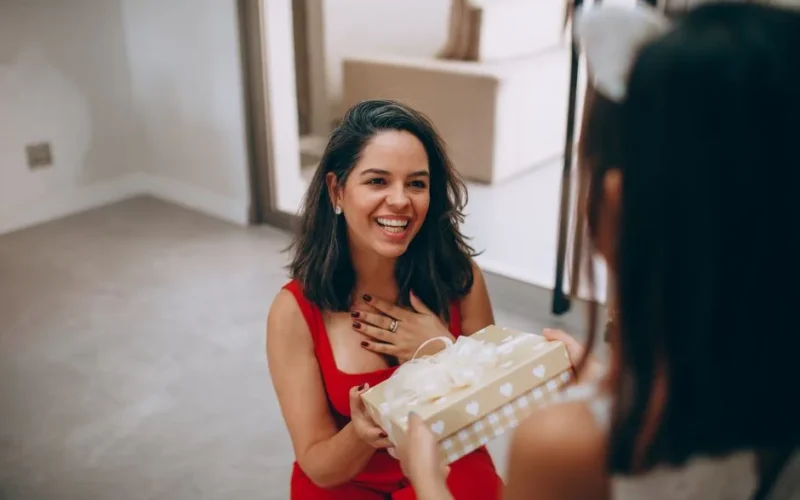 A happy woman receives a gift from her daughter indoors, capturing a moment of joy and connection.