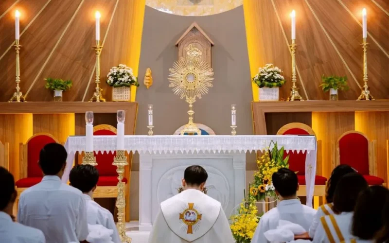 A priest leads a mass ceremony in a beautifully decorated church altar with candles.