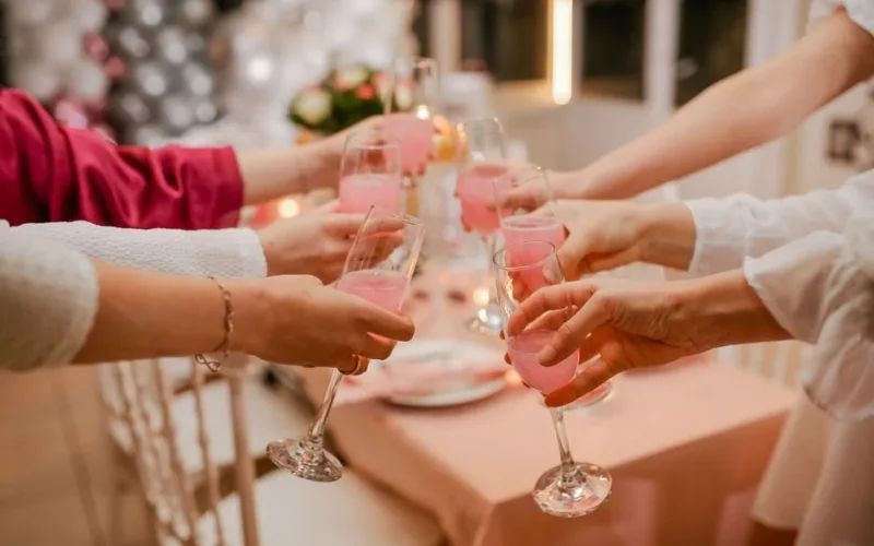 Friends raising pink drinks in a festive toast, symbolizing celebration and togetherness.