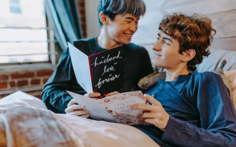 A couple enjoying a heartfelt moment reading romantic cards in a cozy bedroom.
