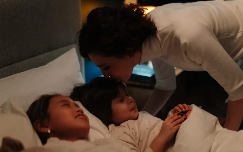 A woman kisses two children goodnight, fostering warmth and comfort for a peaceful bedtime.