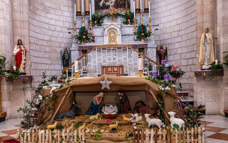 A detailed nativity scene with religious figures and animals inside a church.