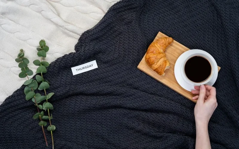 Enjoy a cozy Thursday morning with coffee, croissant, and a warm blanket setup.