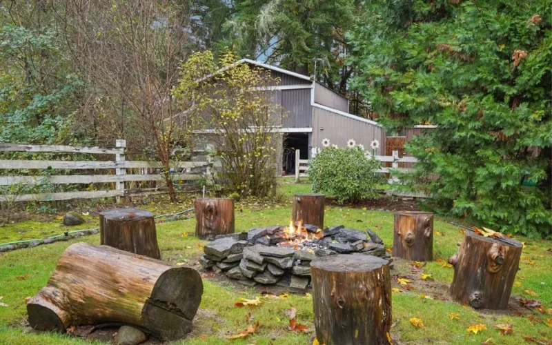 Cozy outdoor fire pit with log stools in a tranquil backyard setting.