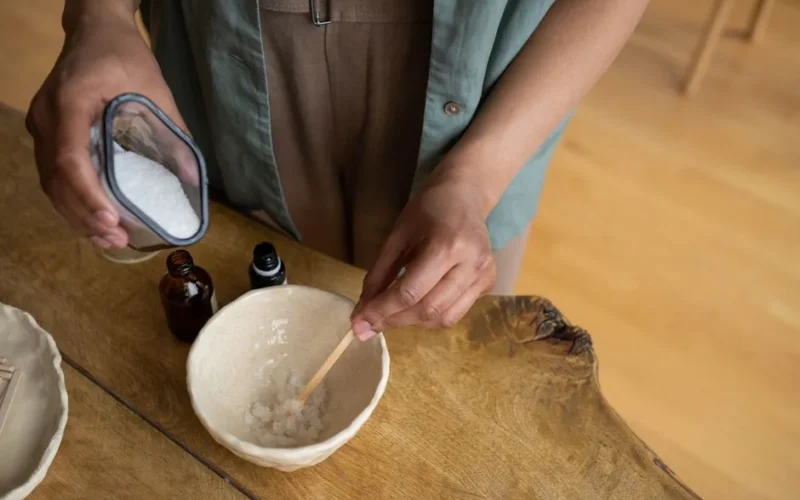 Close-up of hands mixing homemade natural body scrub in a bowl.