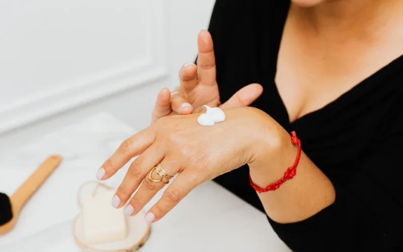 Close-up of a woman applying moisturizing cream to her hands as part of her skincare routine.
