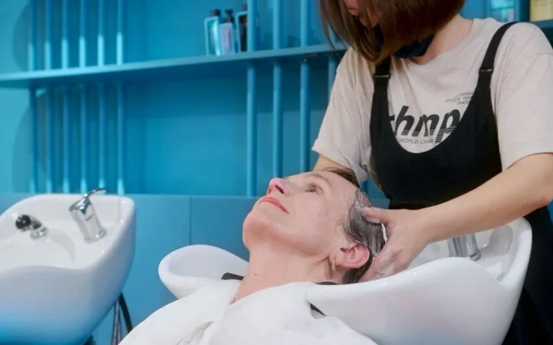 An elderly woman enjoys a professional hair wash at a modern hair salon.