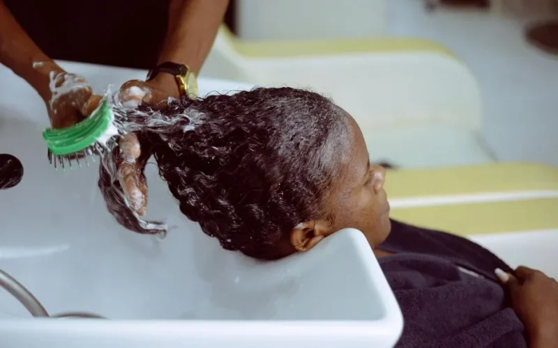A woman receives a hair wash at a salon with foam and care.