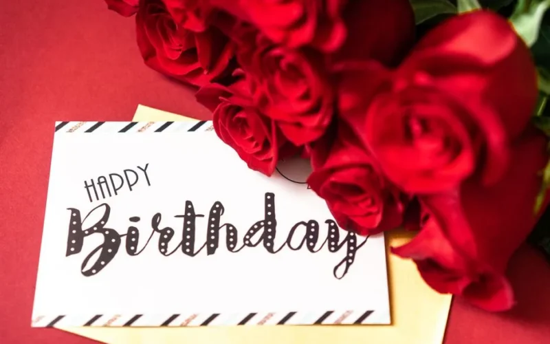 A stylish birthday card surrounded by vibrant red roses on a red background.