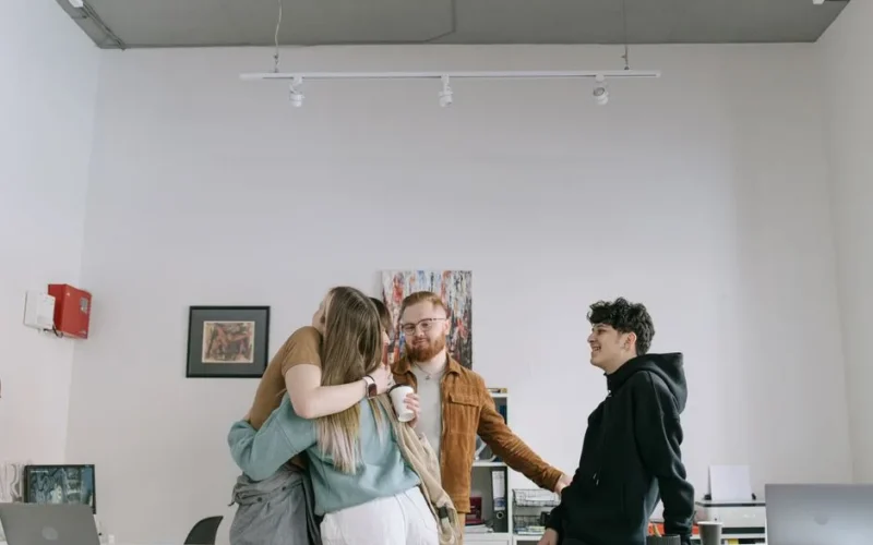 A group of young professionals embracing in a modern office setting, showcasing teamwork and camaraderie.