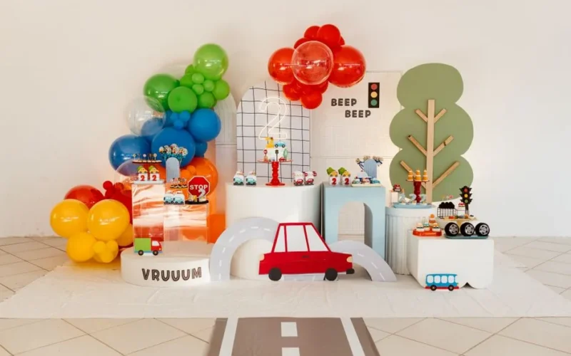 Vibrant transportation-themed children's party setup with balloons and road decorations.