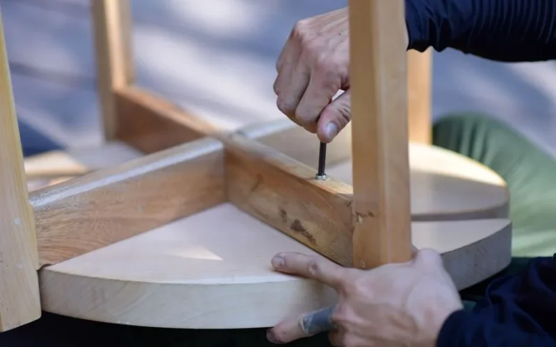 Hands assembling a wooden stool, highlighting craftsmanship and DIY spirit.
