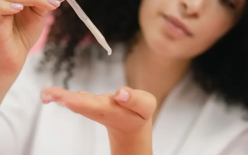 Close-up of a woman applying skincare serum with a pipette, focusing on body care and cosmetic application.