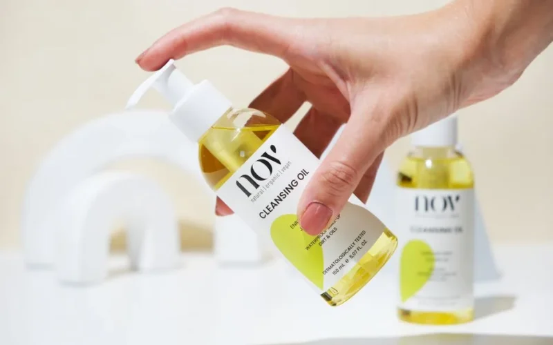 Close-up of hand holding a cleansing oil bottle, perfect for skincare ads.