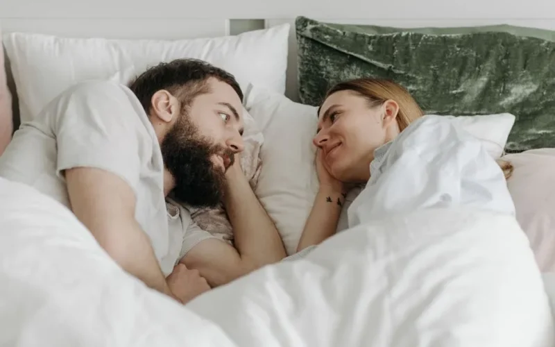 A couple lying in bed sharing a tender moment, conveying love and intimacy.