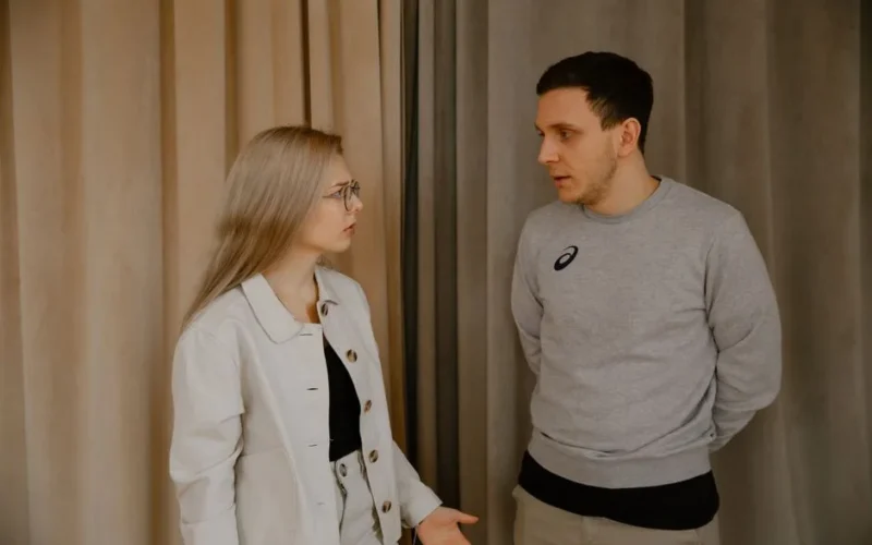 Man and woman having a serious conversation indoors, focused expressions.