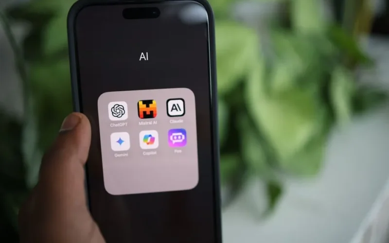 Close-up of a hand holding a smartphone with AI applications on screen.