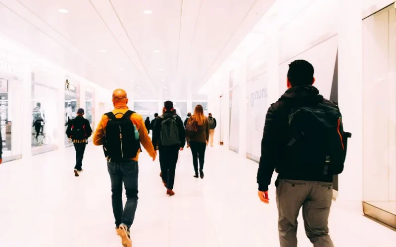 Group of travelers walking through a bright, modern airport terminal carrying backpacks.