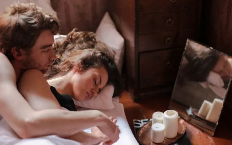 A couple peacefully sleeping together in a cozy bedroom, surrounded by soft candlelight.
