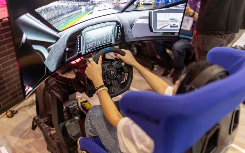 Person using a realistic VR racing simulator at a gaming event, focused on the immersive experience.