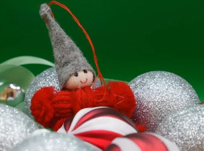 A cheerful elf Christmas ornament surrounded by glittery holiday decorations.