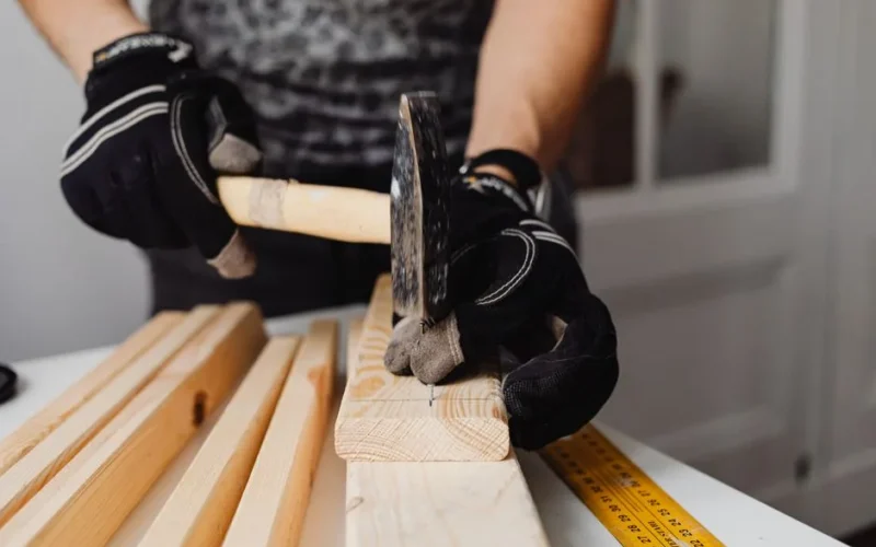 Craftsman hammering nails into wood, showcasing woodworking skills and tools in action.