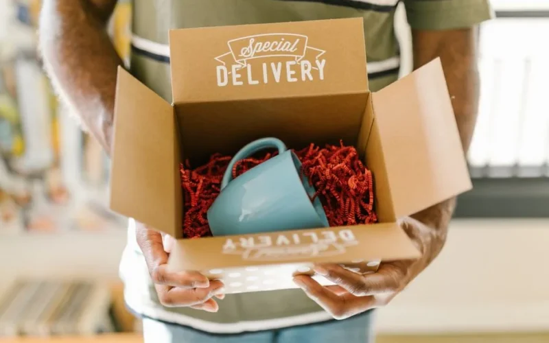 Man holding a box with a special delivery coffee mug inside.