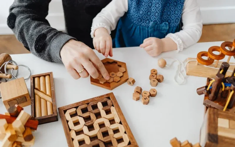 A father and child engaging with wooden educational toys at a table indoors.