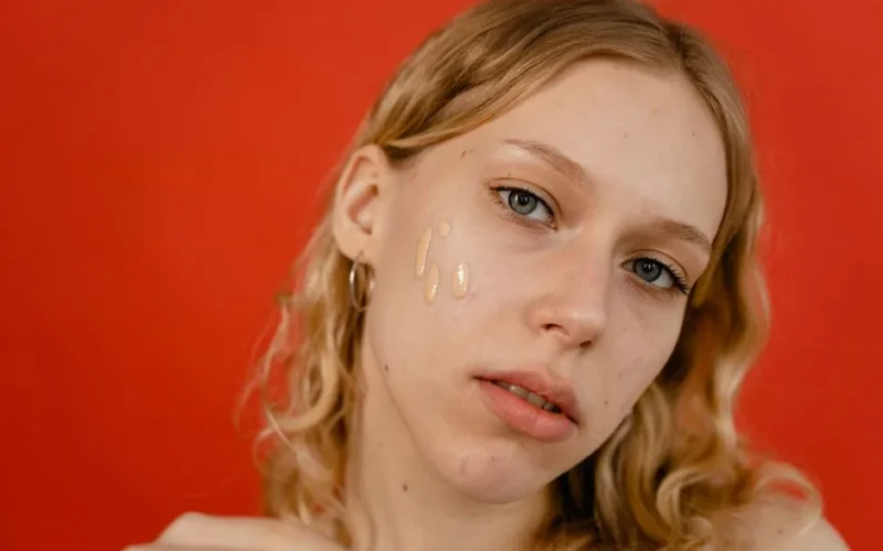 A close-up portrait of a woman applying foundation, showcasing natural beauty and skincare.