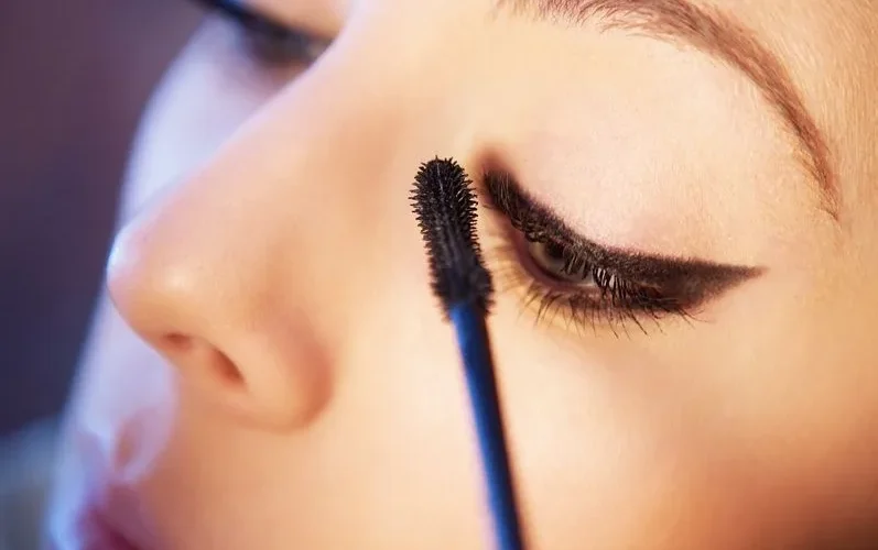 Detailed close-up of a woman applying mascara to enhance her eye makeup look.