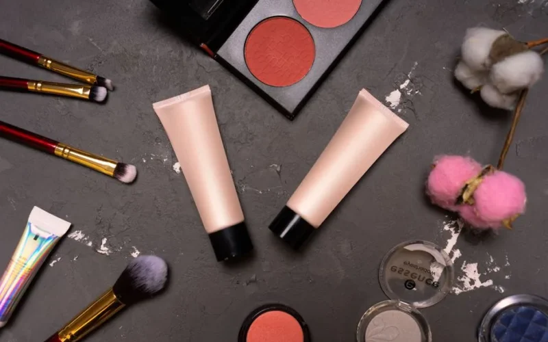 A stylish flat lay showcasing cosmetics including brushes and creams on a dark background.