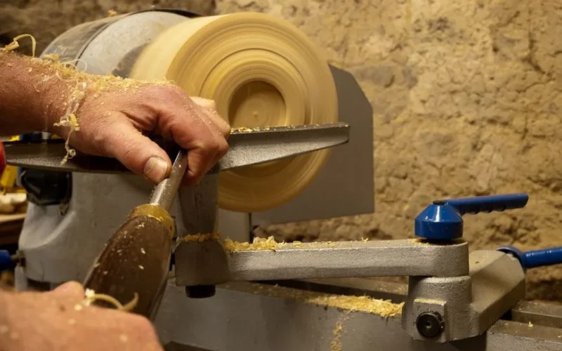 Skilled artisan crafting a wooden bowl using a lathe in a rustic workshop setting.