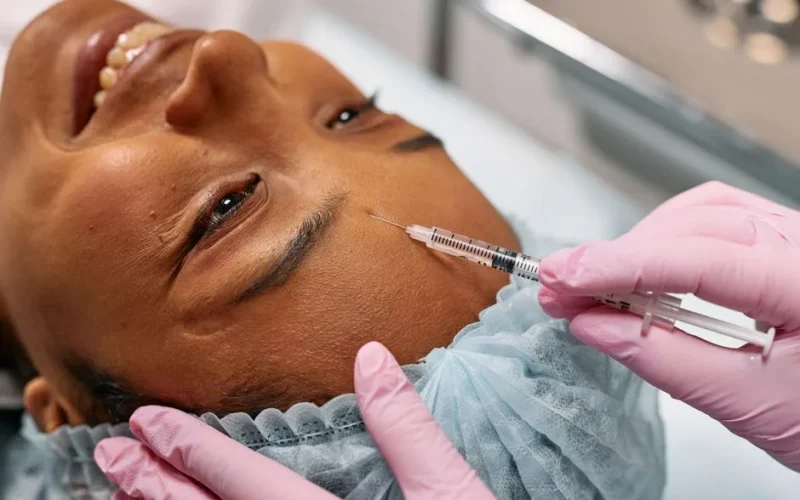 Close-up of a woman receiving a cosmetic injection on her forehead in a clinical setting.
