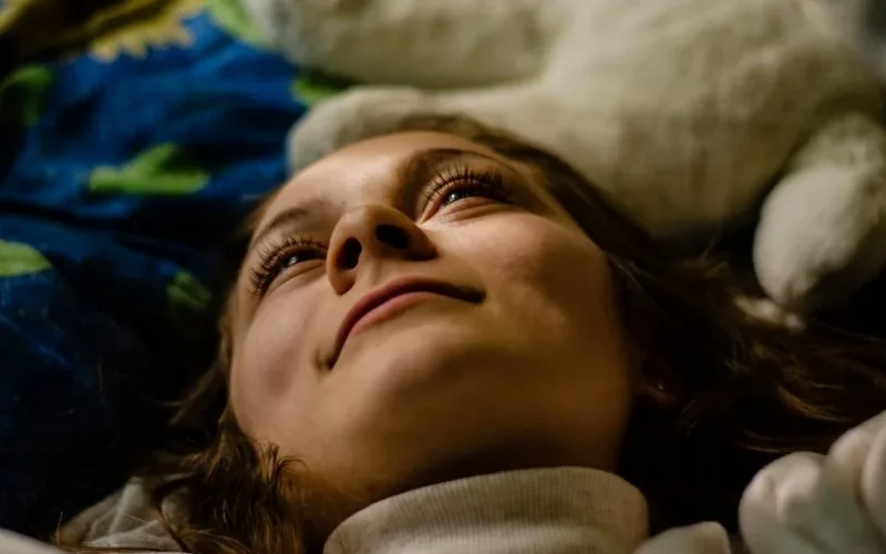 Close-up portrait of a woman lying indoors, looking relaxed and content.