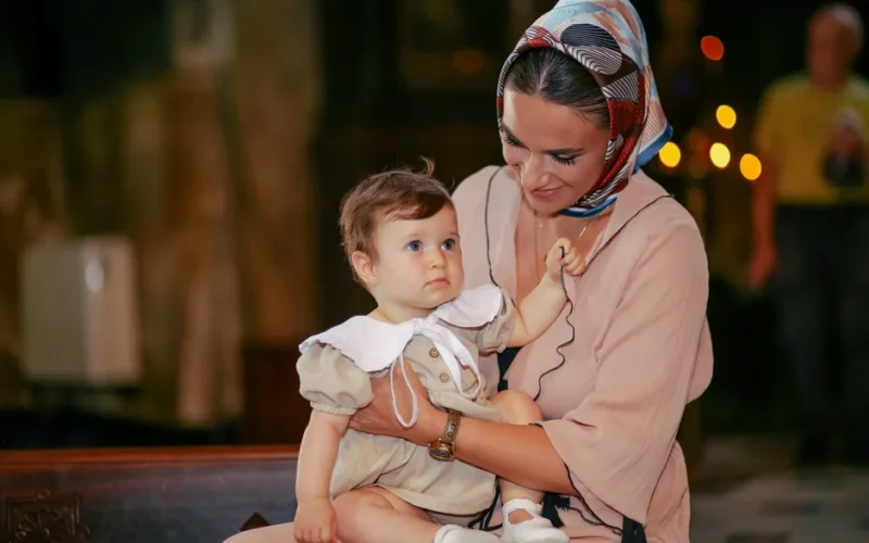 A mother lovingly holds her baby during a church ceremony.