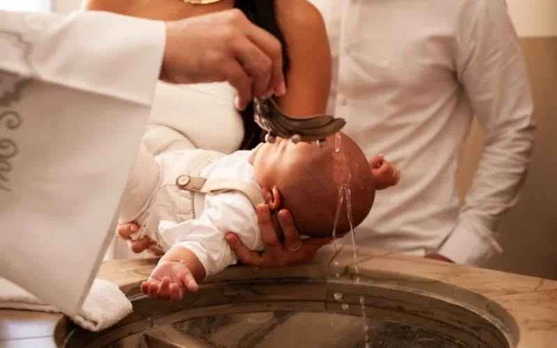 A meaningful baptism ceremony with a baby held by family members in a church setting.
