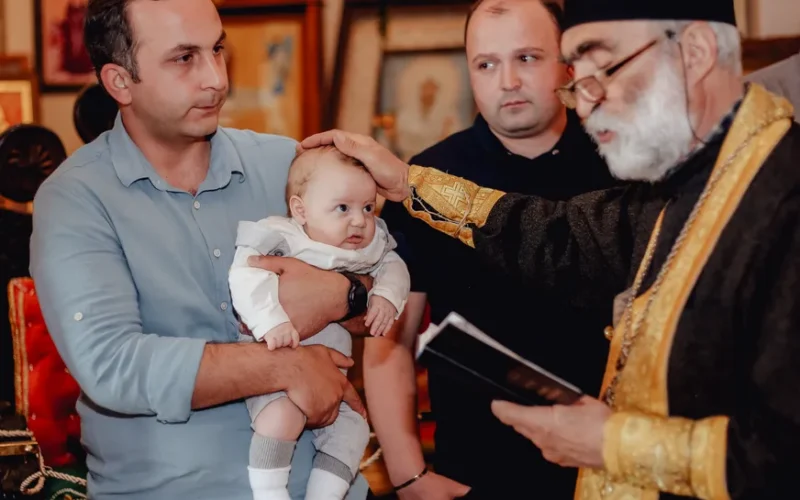 A baby is baptized by a priest in a traditional church ceremony, showcasing a spiritual rite.